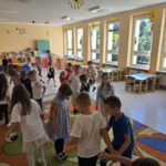 Dzieci w sali przedszkolnej odnajdują swoje kropki na dywanie