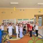 Dzieci podczas zabawy stoją na kropkach i machają