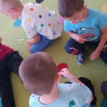 Dzieci przyklejają kolorowe kropki na ubranka swoich kolegów i koleżanek