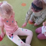 Dziewczynka przykleja kolorową kropeczkę koleżance