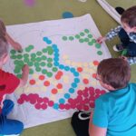 Dzieci układają mapę fizyczną Polski z kropek