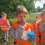 Dzieci podczas akcji "Sprzątanie Świata" wrzucające śmieci do worków
