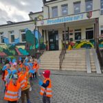 Dzieci ustawione w pary przed budynkiem przedszkola