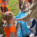 Dzieci podczas akcji "Sprzątanie Świata" wrzucające śmieci do worków
