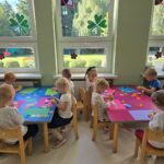 Dzieci wykonujące pracę plastyczna przy stolikach