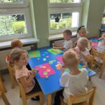 Dzieci wykonujące pracę plastyczna przy stolikach