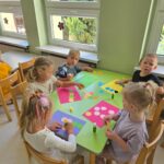 Dzieci wykonujące pracę plastyczna przy stolikach