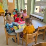 Dzieci wykonujące pracę plastyczna przy stolikach