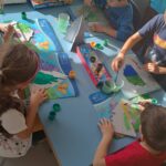 Dzieci w zespole malują choinki z kartonu
