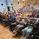 Dzieci siedzą w fotelach w Miejskim Domu Kultury przed przedstawieniem "Dziadek do orzechów"