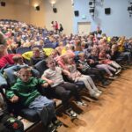 Dzieci siedzą w fotelach w Miejskim Domu Kultury, czekają na przedstawienie "Dziadek do orzechów."