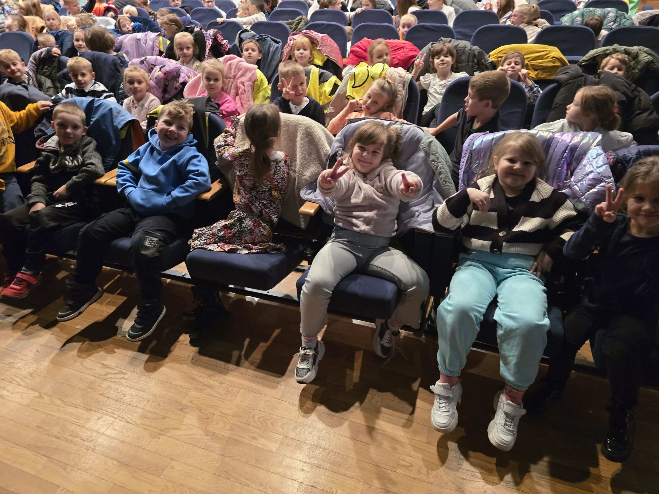 Uśmiechnięte dzieci siedzą w Miejskim Domu Kultury i czekają na przedstawienie "Dziadek do orzechów".