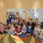 Przedszkolaki wraz z Kubusiem Puchatkiem wspólnie pozują do zdjęcia w sali przedszkolnej.