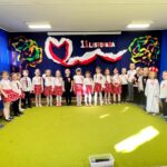 Dzieci stoją na tle dekoracji z okazji 11 listopada.