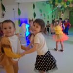 Dziewczynka i chłopiec śmieją sie oraz trzymają się za ręce i tańczą