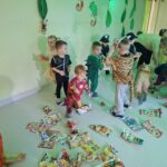 Dzieci w strojach karnawałowych tworzą śnieżki z papierowych kartek