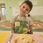 Chłopiec z własnoręcznie przygotowaną pizzą