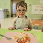 Chłopiec z własnoręcznie przygotowaną pizzą