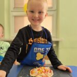 Chłopiec z własnoręcznie przygotowaną pizzą