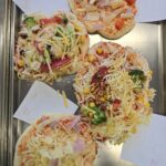 pizze przygotowane przez dzieci na blaszce do pieczenia przed włożeniem do piekarnika
