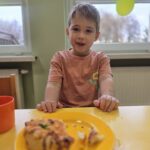 Chłopiec przy stoliku z własnoręcznie przygotowaną pizzę