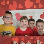 Czworo chłopców pozuje do zdjęcia w czerwonej ramce z sercami.
