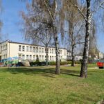 Budynek przedszkola widziany z perspektywy placu zabaw w otoczeniu zieleni