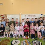 Grupa przedszkolna siedząca na krzesłach na dywanie