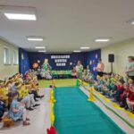 Przedszkolaki siedzą wokół wybiegu, czekają na pokaz mody ekologicznej.
