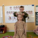 Chłopczyk zakładający papierową koronę dziewczynce w złotej sukience