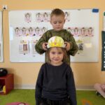 Chłopczyk w zielonej bluzie zakładający koronę dziewczynce w czarnej bluzce