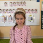 Dziewczynka w różowej sukience z papierową koroną na głowie