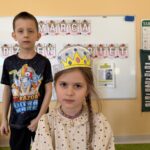 Dziewczynka w kolorowej papierowej koronie i chłopczyk w czarnej bluzce z nadrukiem
