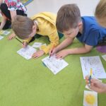 Chłopcy na dywanie rozwiązaują zadania.