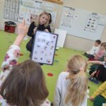 Pani pokazuje dzieciom tablice przedstawiającą jak dbać o środowisko.