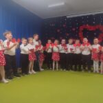 Grupa dzieci ubranych elegancko śpiewa piosenkę.
