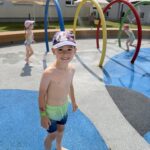 Dzieci w strojach kąpielowych na wodnym placu zabaw