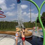 Dzieci biegające w strojach na wodnym placu zabaw