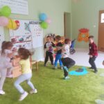 Dzieci tańczące do muzyki w przedszkolnej sali