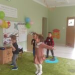Dzieci tańczące do muzyki w przedszkolnej sali
