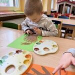 Chłopiec obijający farbę palcami na jesiennym drzewie