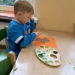 Chłopiec obijający farbę palcami na jesiennym drzewie
