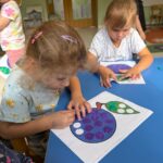 Dziewczynki wykonujące przy stoliku pracę plastyczną