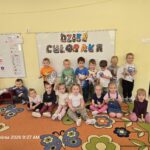 Grupa przedszkolaków pozuje do zdjęcia w sali przedszkolnej.
