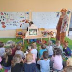 Pani bibliotekarka przedstawia dzieciom teatrzyk kamishibai