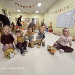 Trzech chłopców i dwie dziewczynki pozują do zdjęcia z gąsienicami z liści oraz sówkami ze słoików.