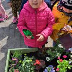 Dziewczynka sadzi kwiatki.