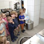 Zdjęcie to przedstawia gromadkę dzieci w kuchni podczas lekcji gotowania.