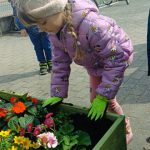 Dziewczynka sadzi kwiatuszki.